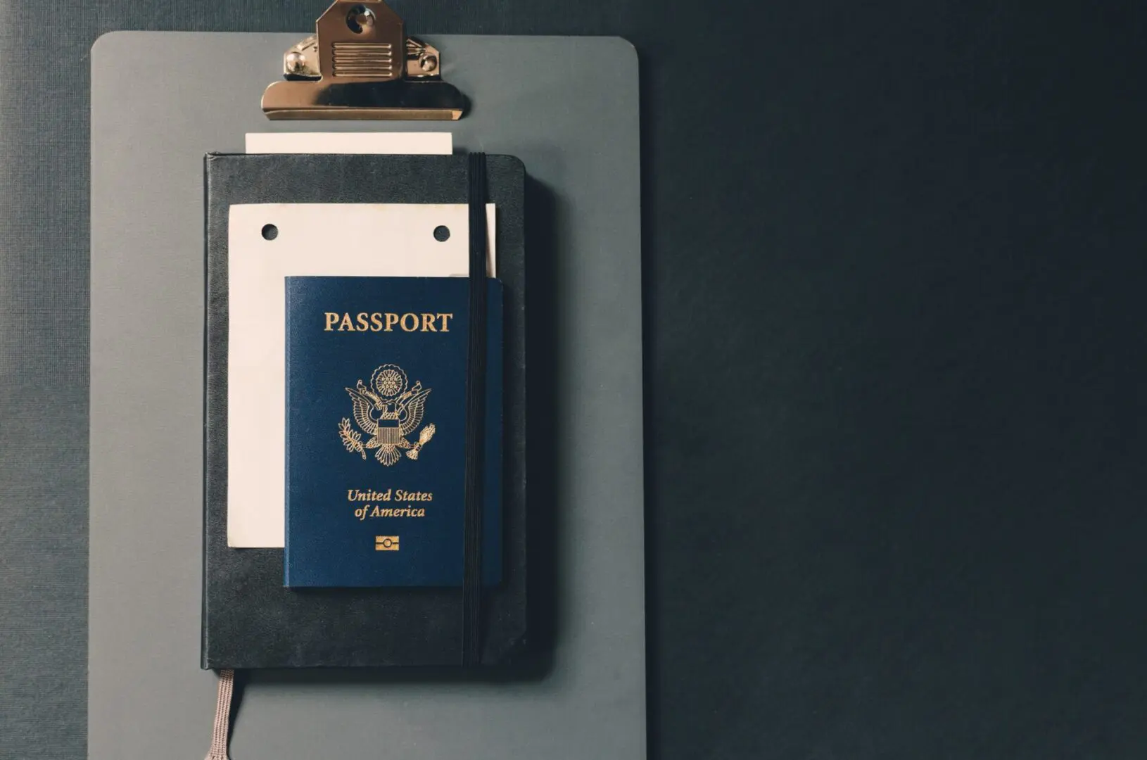 USA passport on top of a black notebook and a clipboard